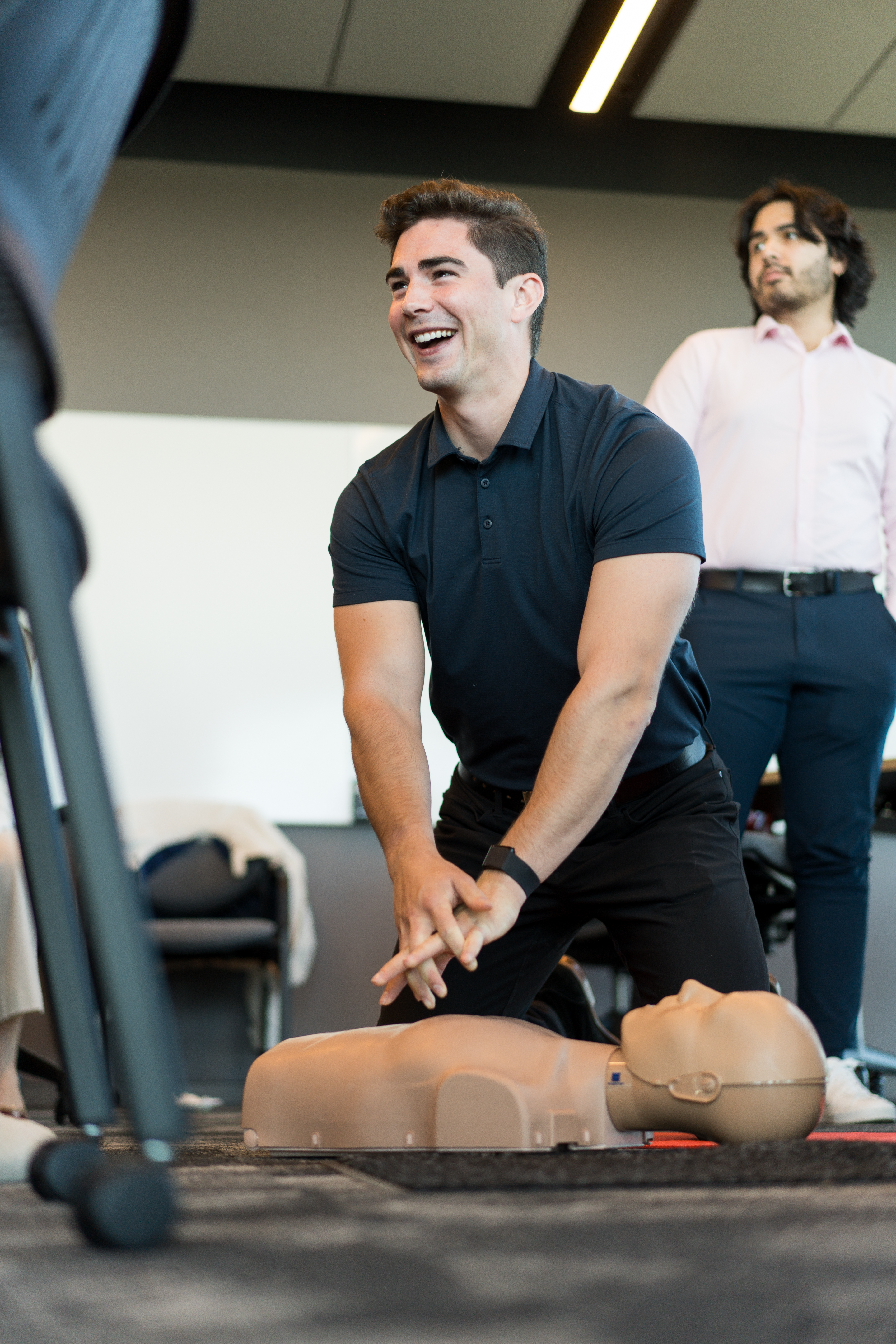 Person smiling as they practice chest compressions on a CPR mannequin.