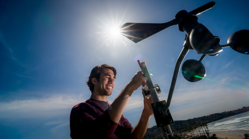 graduate student checks a weather monitoring station.