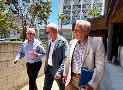 Three older men walking outside looking away from the camera
