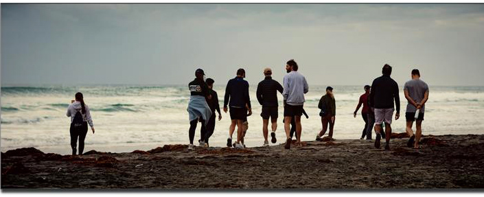 Backs of a group of people hiking on the beach