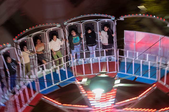 View of students riding the Round Up ride that turns quickly in a circle and tilts to the side.