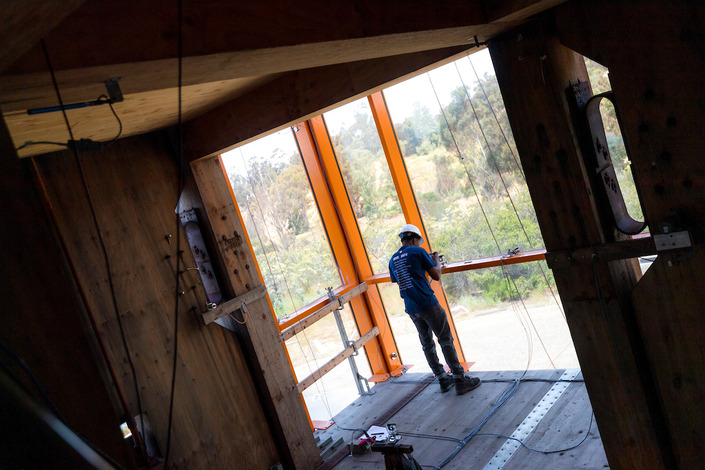 Researcher peers outside standing on an upper floor of the building.