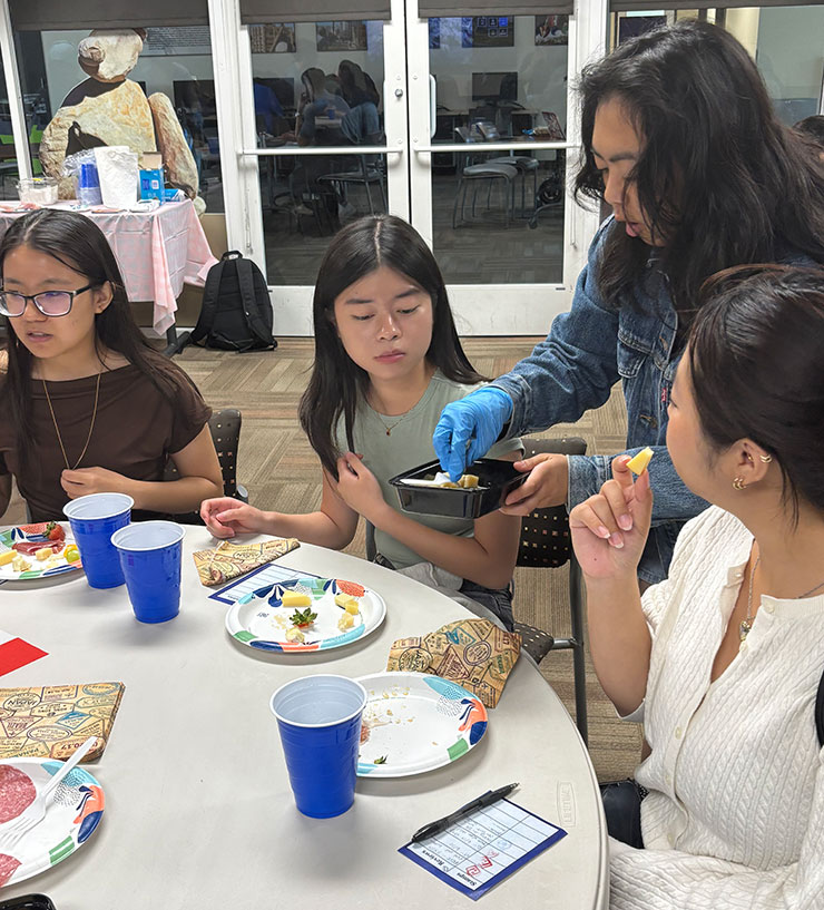 A person serves cheese to a table of people