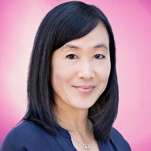 Photo of woman with dark hair with slight smile against pink background