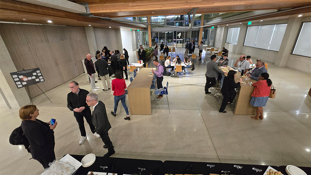 Wide shot of faculty networking in a reception atrium.