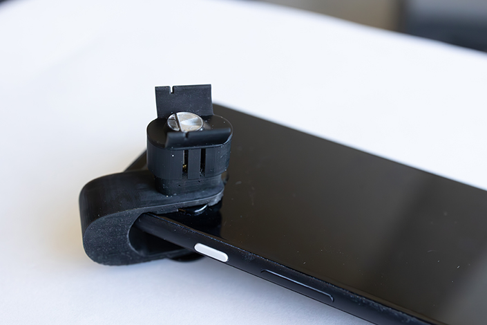 Black smartphone with a black plastic clip attached to one corner.