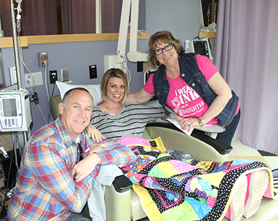 Michelle in infusion chair with husband and mom on either side