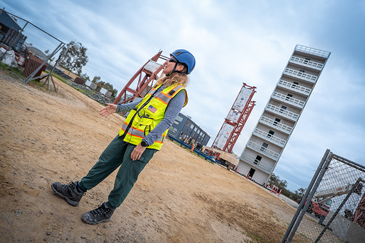 Portrait of professor Tara Hutchison with the 10 story building in the background