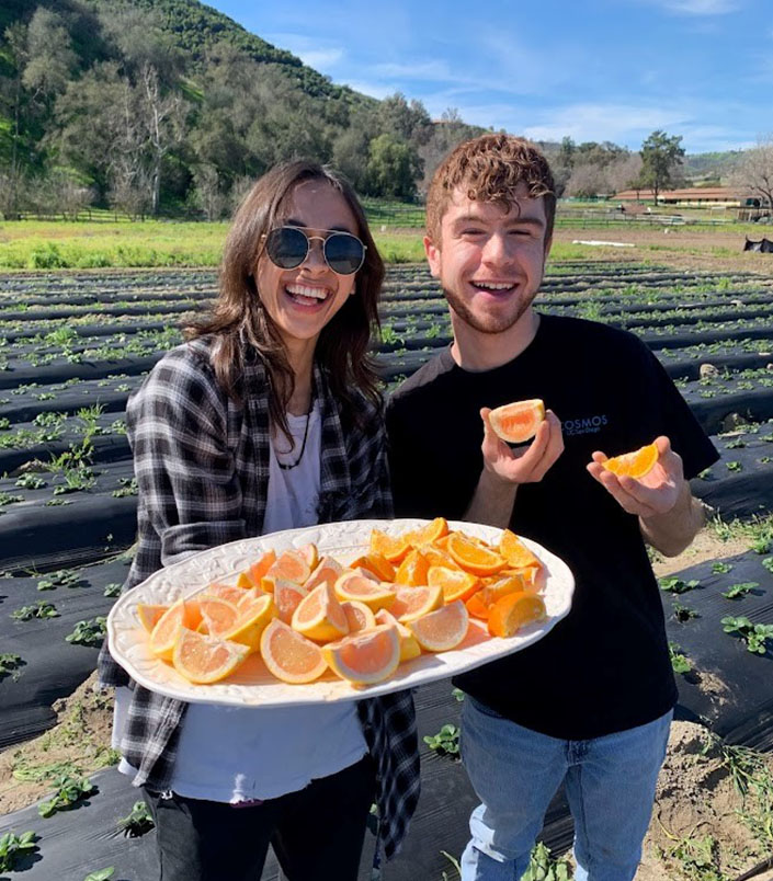 Students offer fresh-cut citrus with farm in background