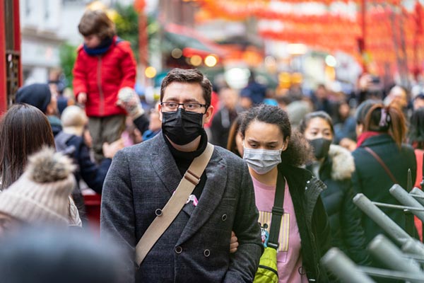 Masked people in a crowded city - Photo by iStock_Powerofflowers