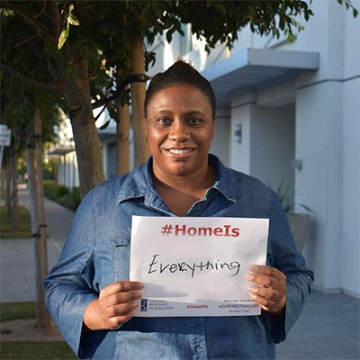 HEART Fellow holds sign saying "Home is everything"