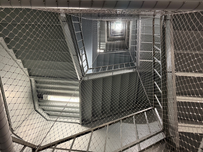 View looking up through a staircase in the Geisel library with safety netting pictured around the railing.