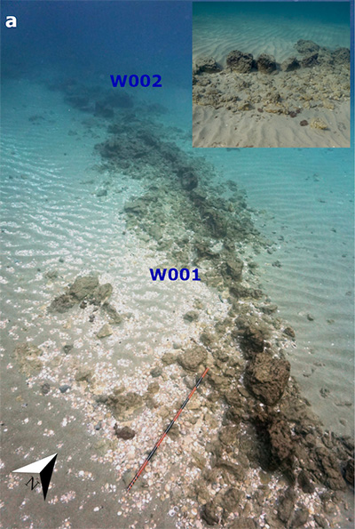 Two walls of stone lie on a seabed.