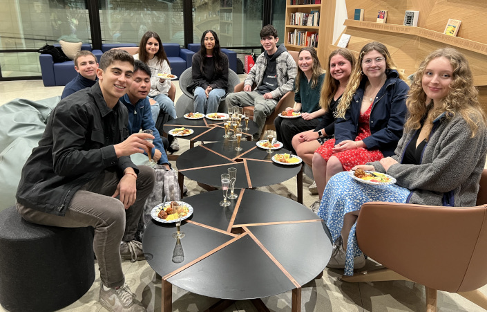 Students sit around tables eating during first Shabbat meal.