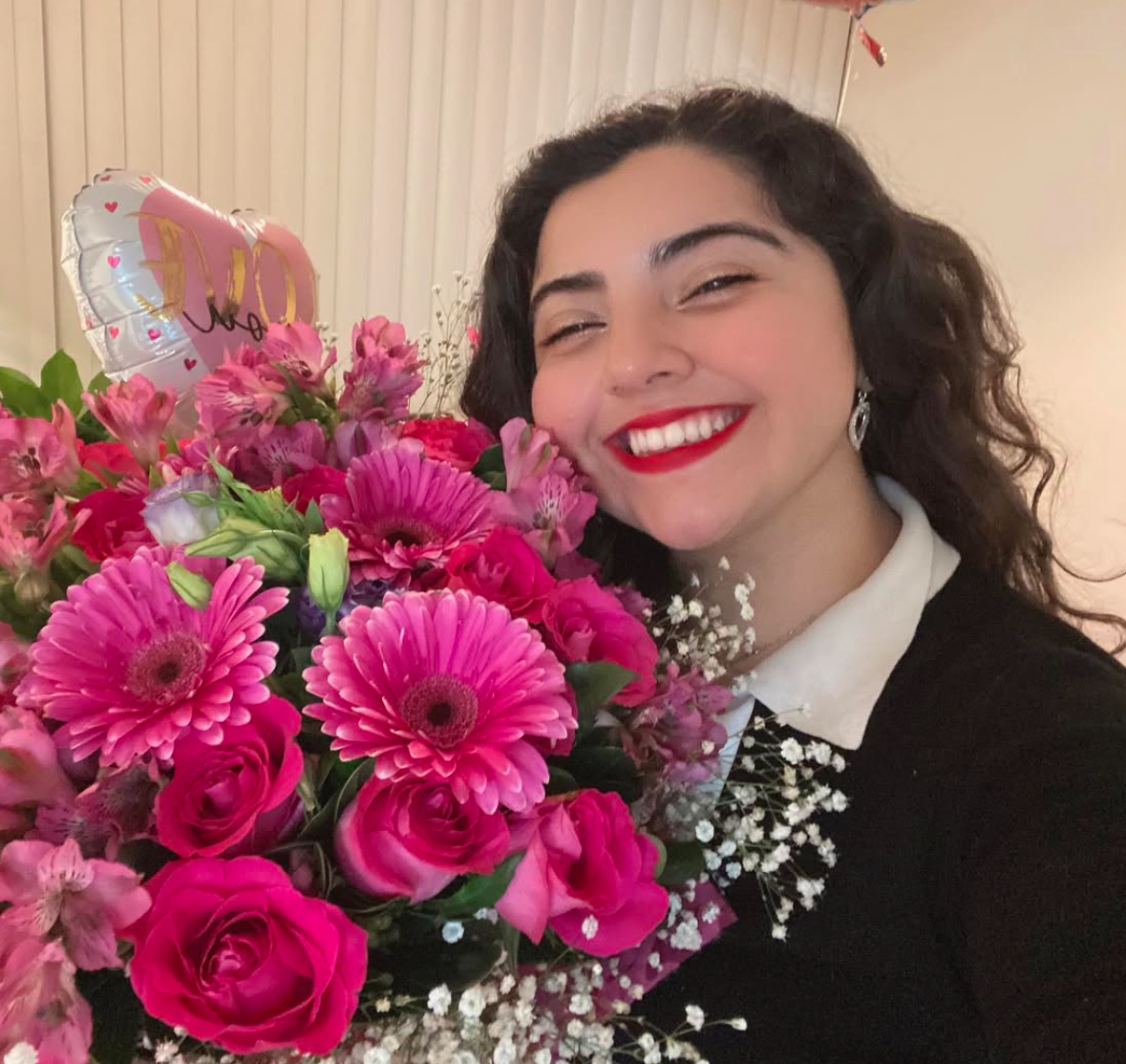 Student smiles with a bouquet of flowers
