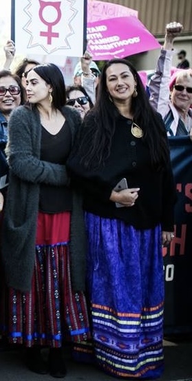 Two people wearing ribbon skirts at a protest