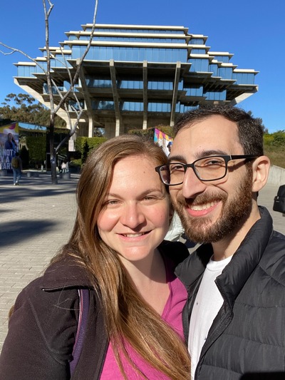 Couple smile for a selfie in front of Geisel Library