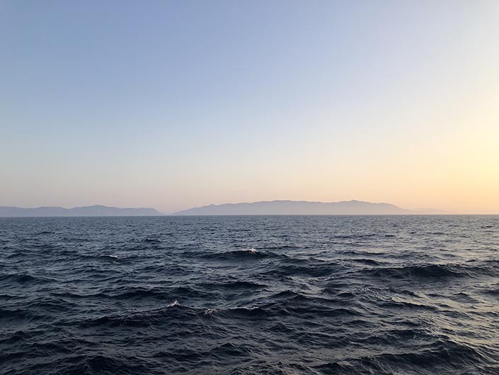 The ocean at sunset, with the coastline in the distance.