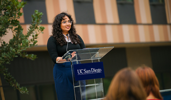 Isha Khirwadkar speaking at podium.