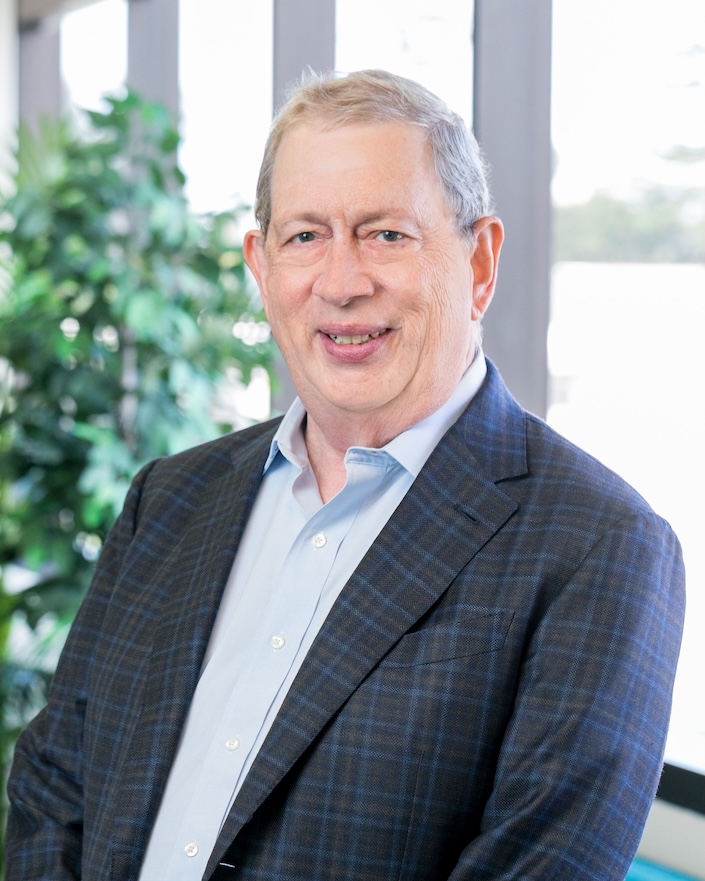 Photo of man with gray hair with plant in background