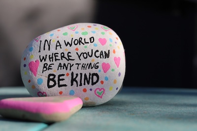 Rock painted with hearts and slogan reading 