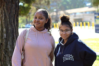 Two high school seniors from Madison High School pose together under a tree in Town Square at UC San Diego.