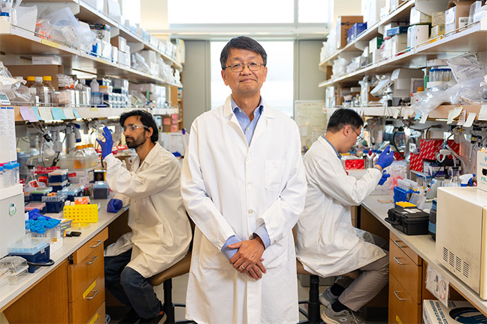 Three researchers in their white coat lab posing for camera.