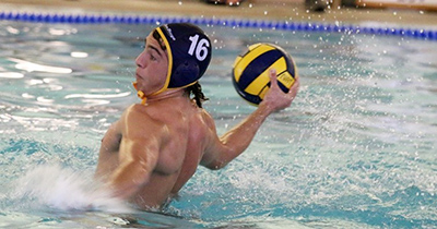 A member of the men's water polo team is shown in the pool about the throw the ball.
