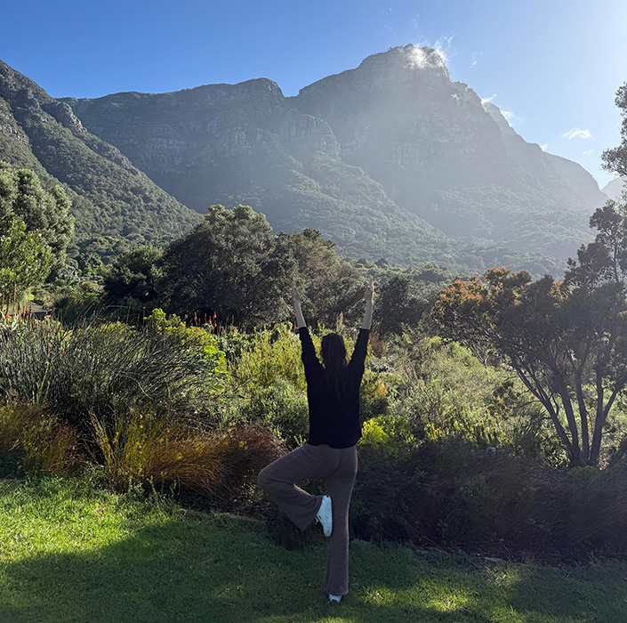 A person practicing yoga in a lush, green, mountainous landscape.