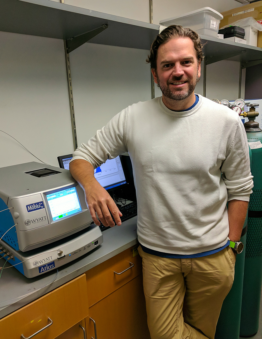 Researcher poses in front of lab equipment