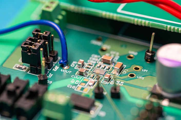 A green circuit board with small golden chips and other small parts.