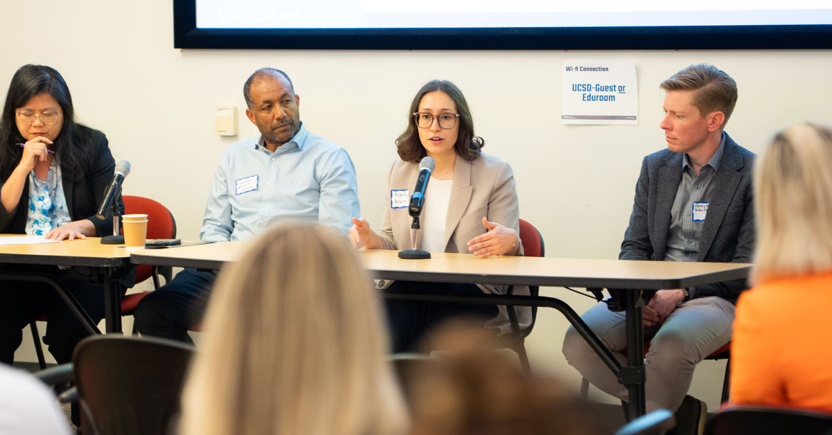 Four panel members seated in front of an audience.