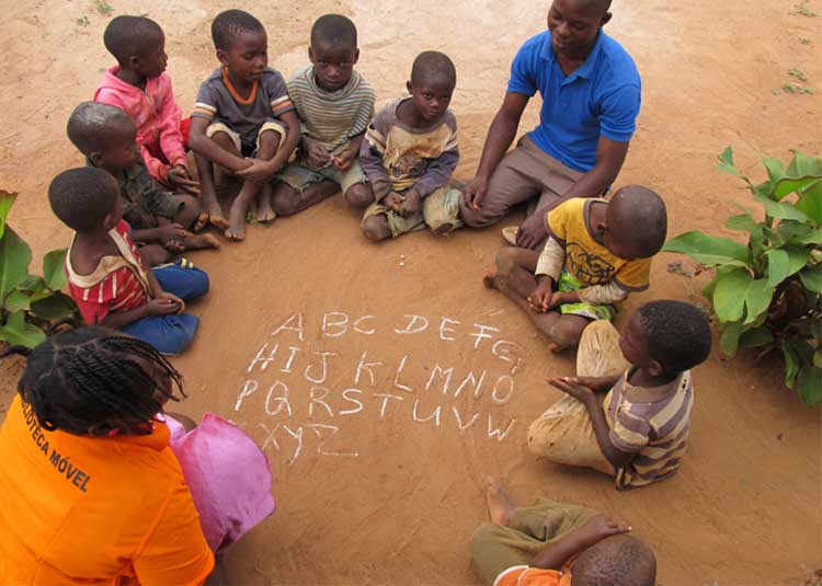 Image: Two Peace Corps volunteers practicing the alphabet with children in Mozambique