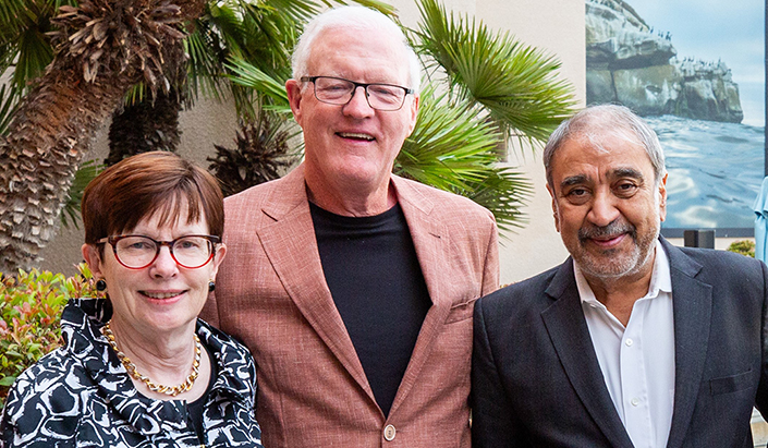 Photo of Paula and Brian Powers with Chancellor Pradeep Khosla in front of a palm tree.