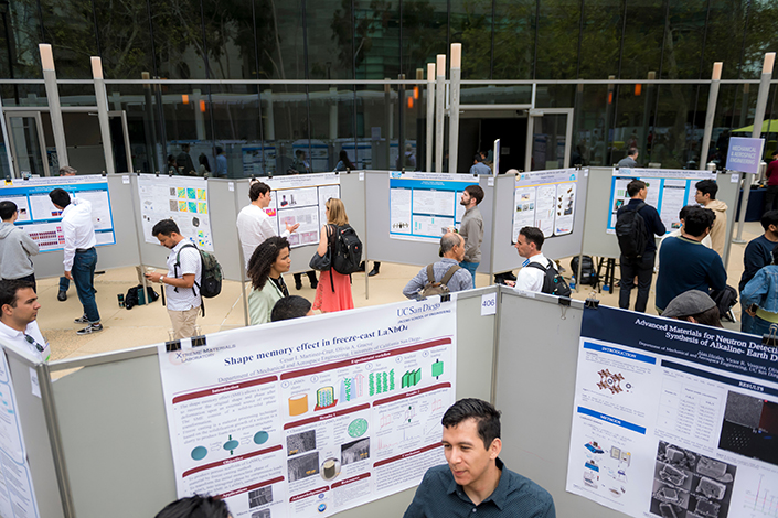 People standing and talking in front of walls of research posters.