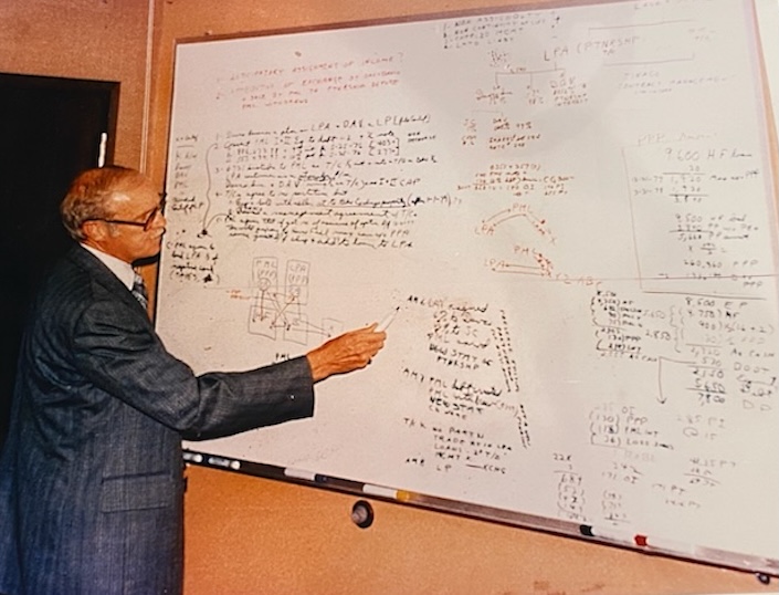Man in front of whiteboard with many notes and equations
