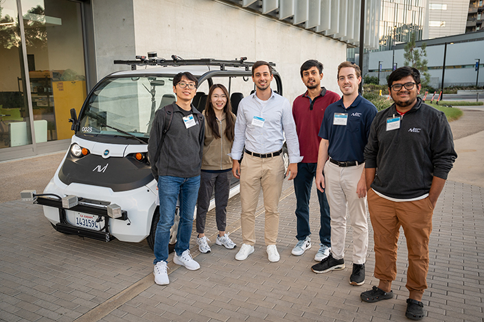 People standing next to a golf-cart-like vehicle.