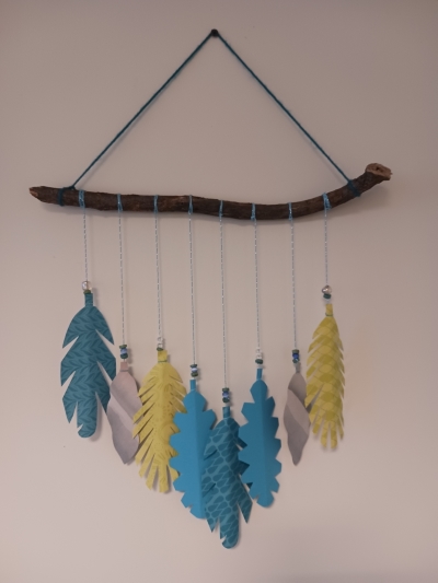 Art piece made by Valencia that has feathers tied to a branch
