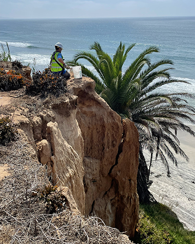 Researchers in safety equipment install a sensor at the top of a cliff. 