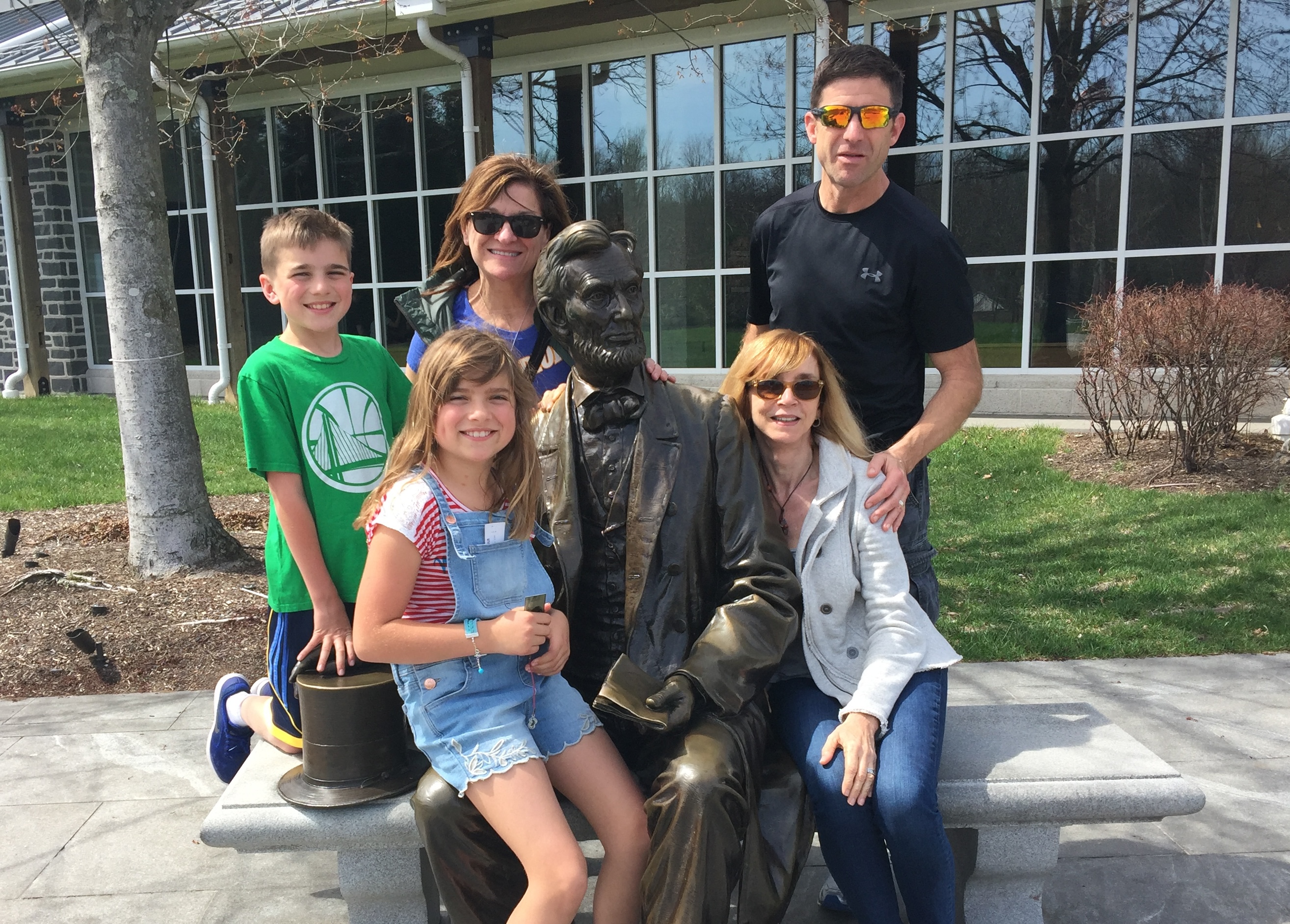 Group of five people posting with Abraham Lincoln statue