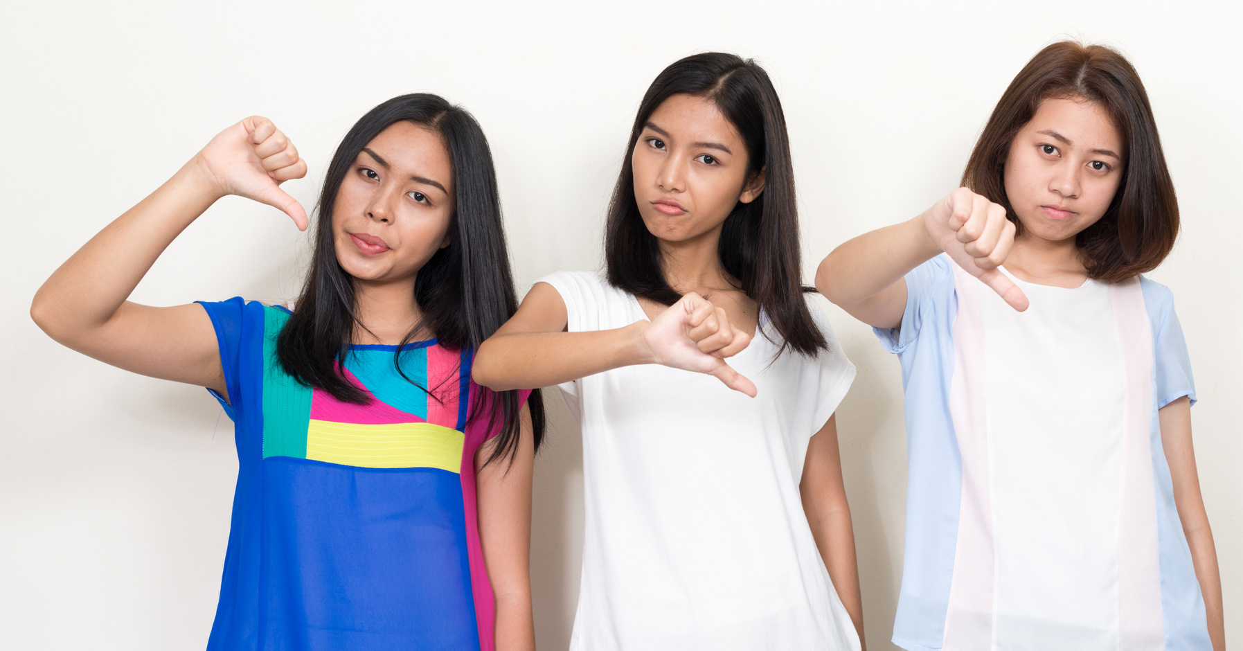 Three young women give a thumbs down