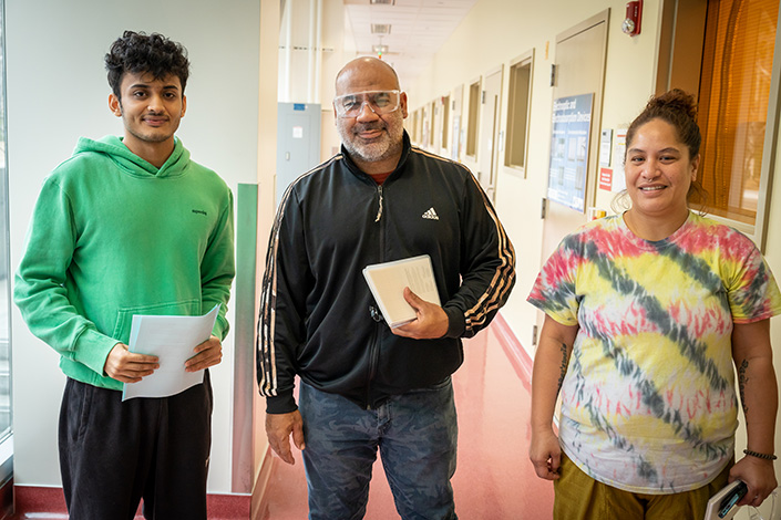 Jacobs School of Engineering undergraduate Chodvadiya stands with trainees Marlon Mendoza, center, and Hauoli Kalui, right, outside the Nano3 cleanroom facility.