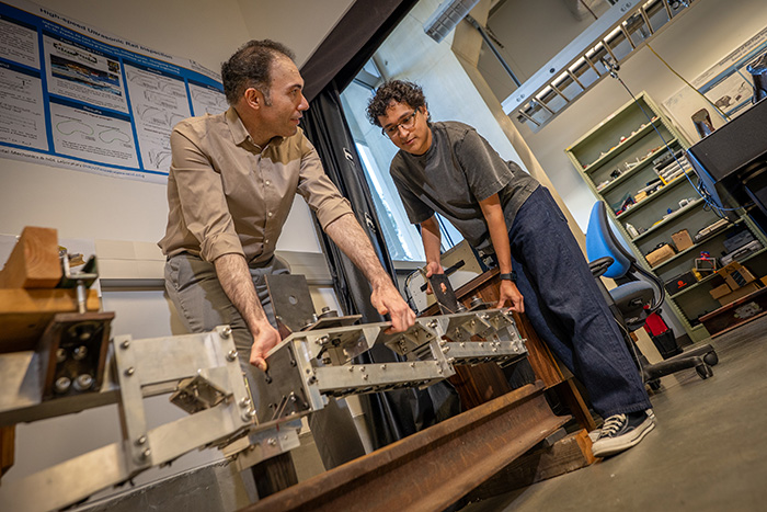 two graduate students hold a metal frame with sensors embedded