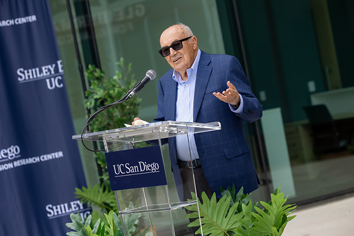 Photo of man speaking behind a podium with sunglasses