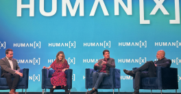 Four people sit in chairs on stage for panel discussion.