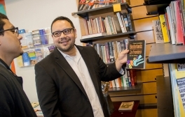 Gerardo Arellano pulls a book of the shelf for a scholar he is speaking with.