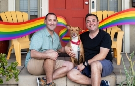 Justin Meyer sits with his husband and their dog on their front porch.
