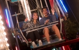 Two UC San Diego students pictured riding a Ferris Wheel at night with lights twinkling around them during the Festival on the Green.