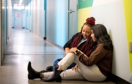 Triton CORE program manager Ashley Metoyer sits in a hallway with a student to discuss wellness plans.