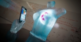 A bust of a torso and breasts next to a smart phone. 